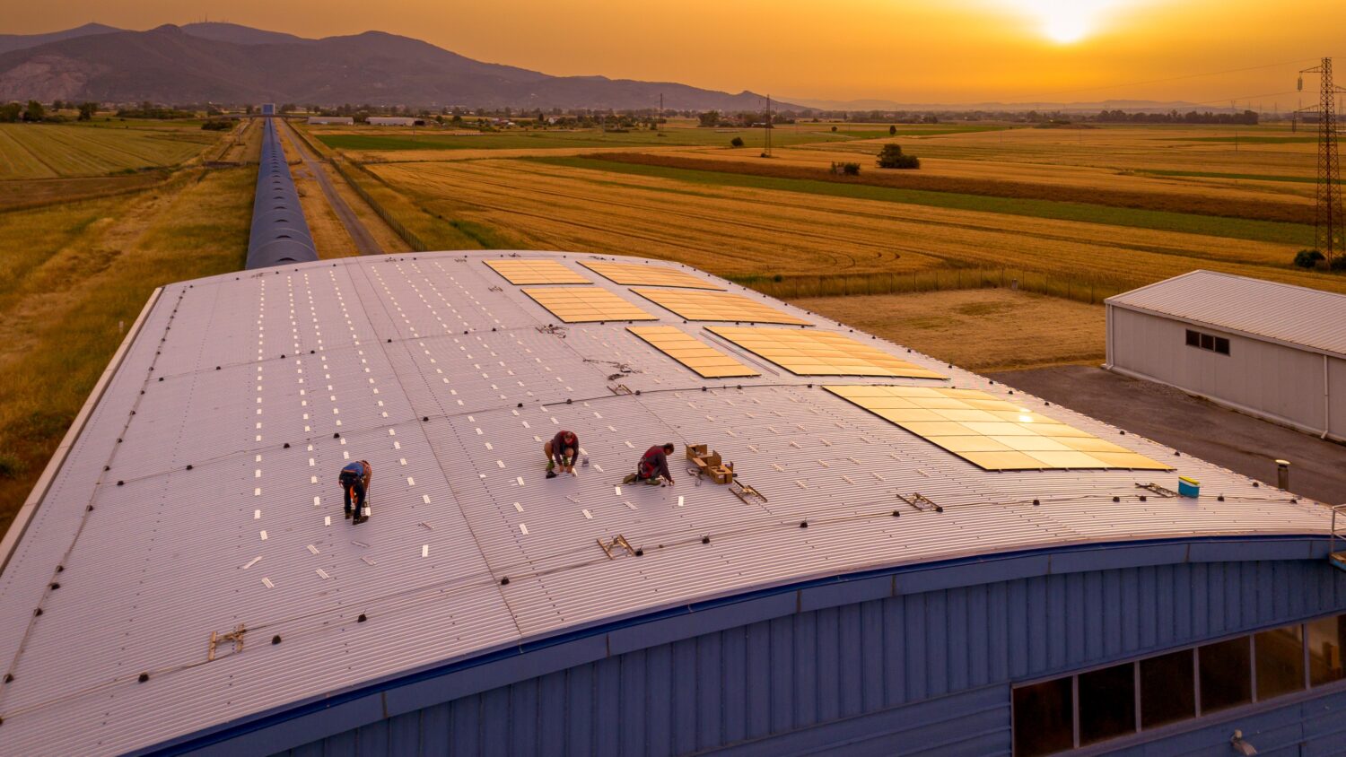 An image shows people working on the roof of the hangar. Solar panels being installed on top of one of the buildings of the Virgo detector. Credits: Massimo D’Andrea/EGO-Virgo