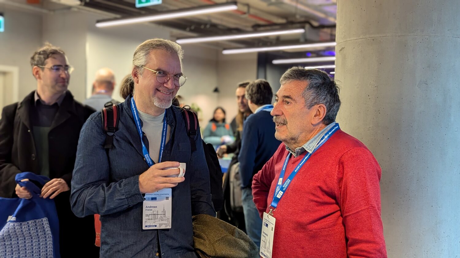 The photo shows a group of people chatting during the ET annual meeting in Warsaw 2024.