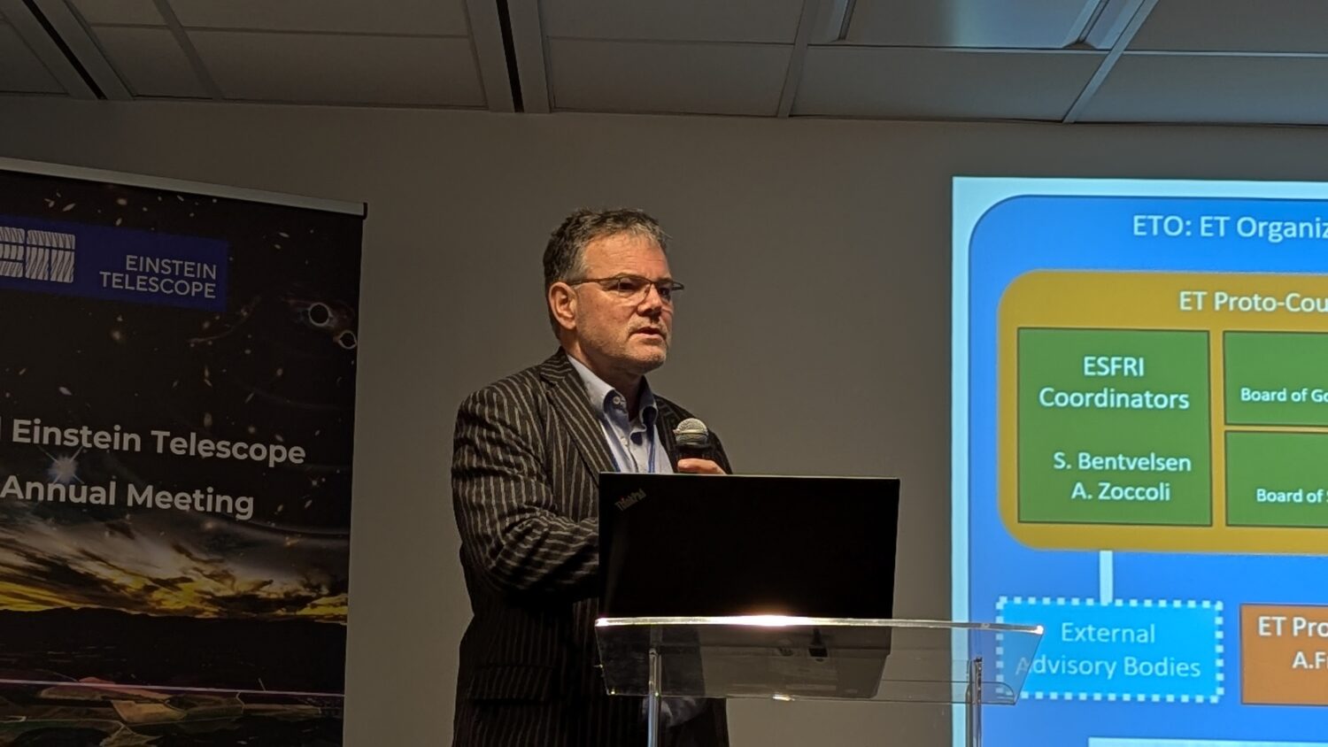 The photo shows a man presenting on stage during the ET annual meeting in Warsaw 2024.