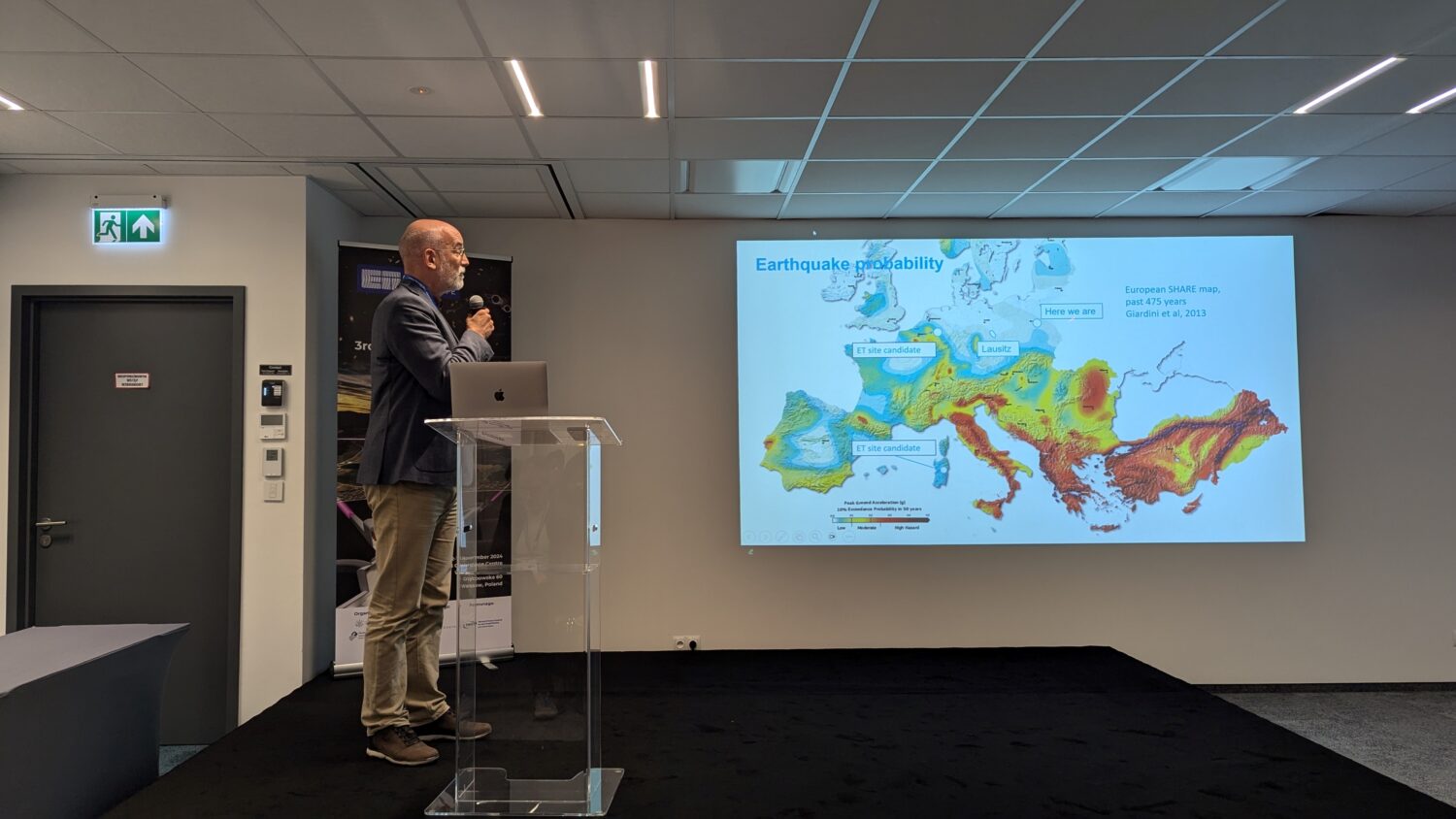 The photo shows a man presenting on stage during the ET annual meeting in Warsaw 2024.