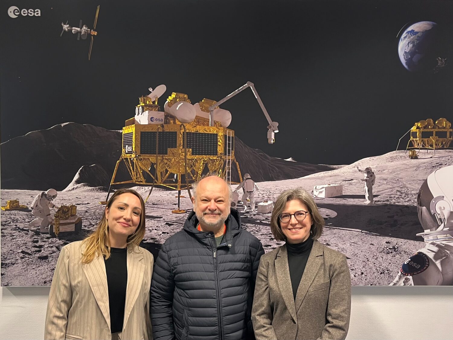 Three people posing in front of a space image