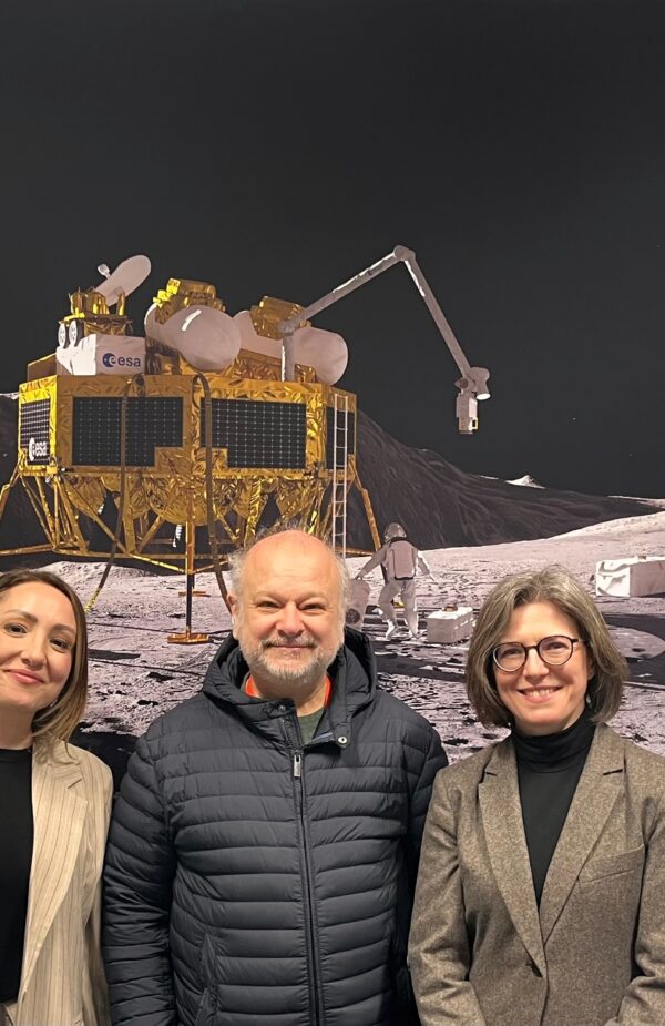 Three people posing in front of a space image